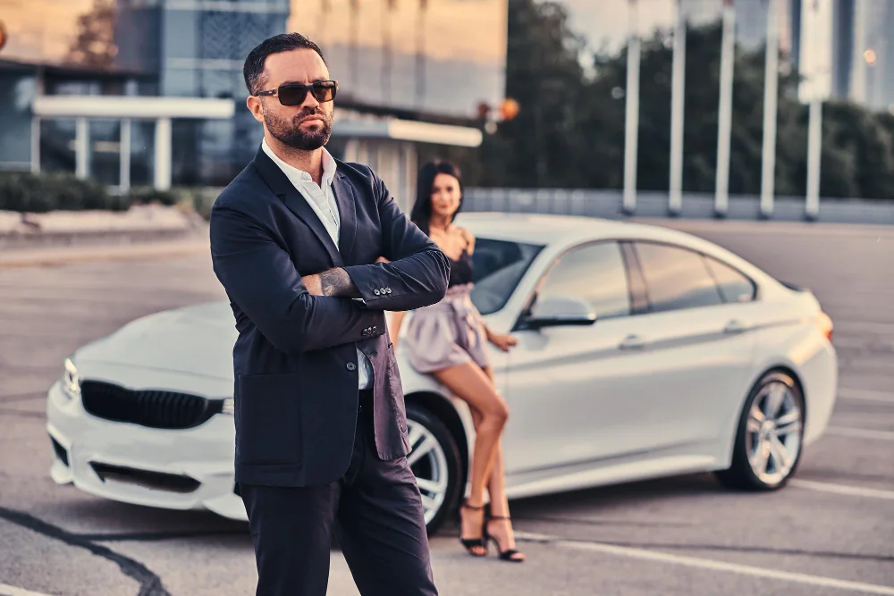 Confident adult man beside a luxury car